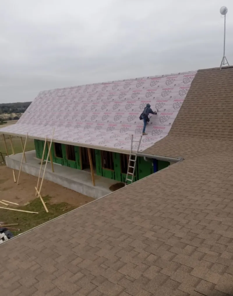 Worker preparing underlayment for a metal roof installation in Colchester